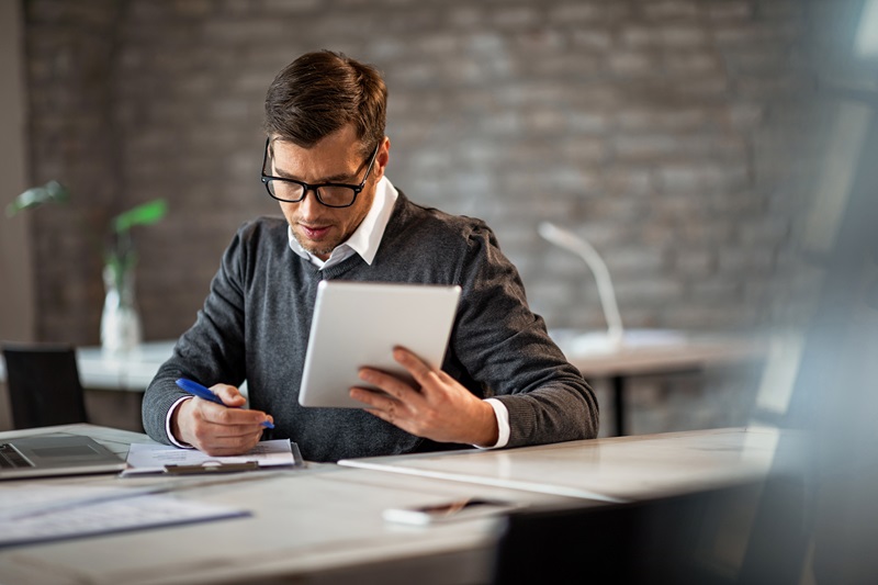 Businessman writing financial reports and using digital tablet i deskundig rapport