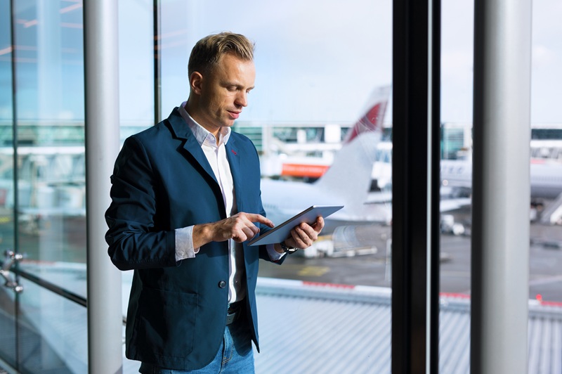 Businessman using tablet computer in airport verzekeringstaxatie