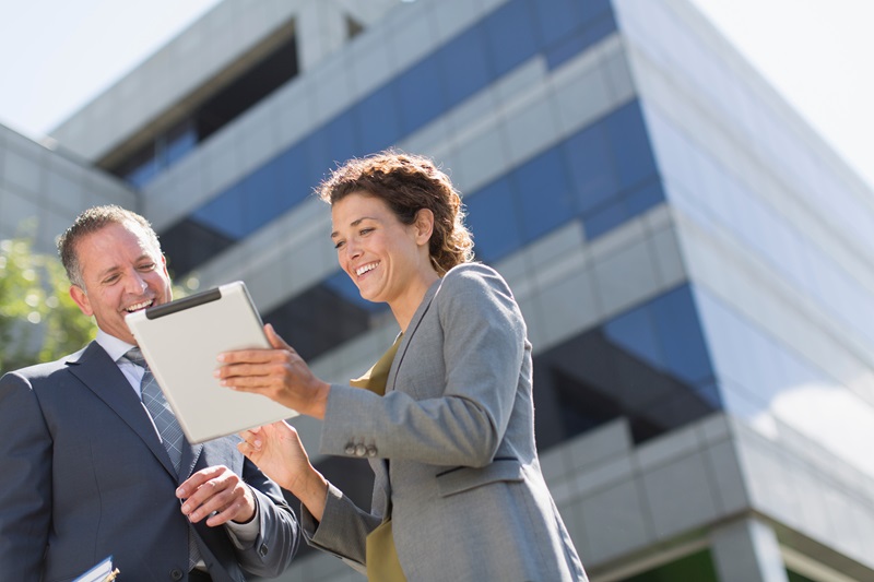 Business people using digital tablet outside office building Verzekeringstaxaties