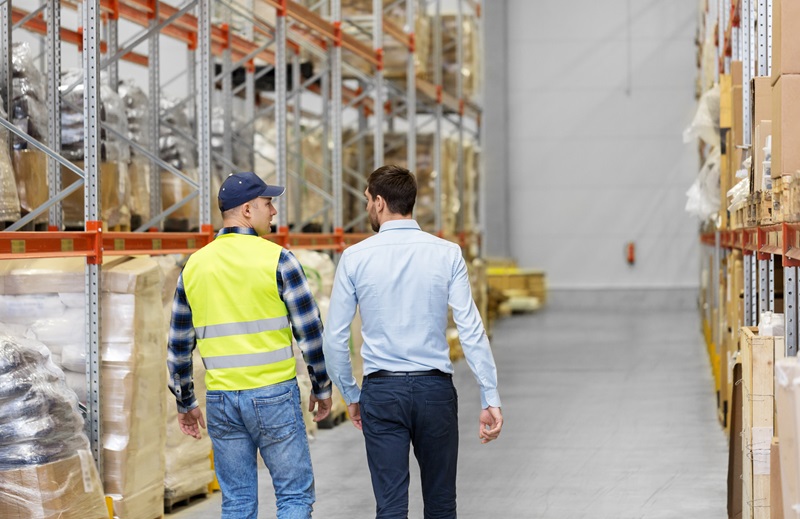 worker and businessman walking along warehouse